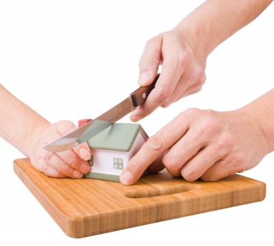 Hands cutting a model home in half